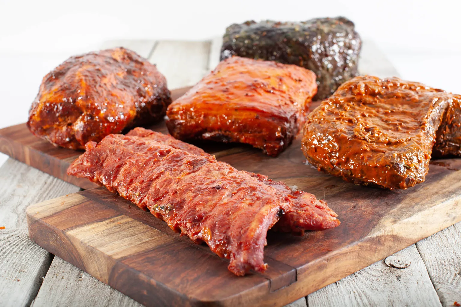 Marinerede spareribs og grillstege på et skærebræt, klar til grillbuffet